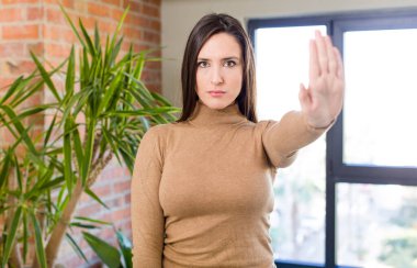 Genç ve güzel bir kadın ciddi, sert, hoşnutsuz ve kızgın görünüyor.