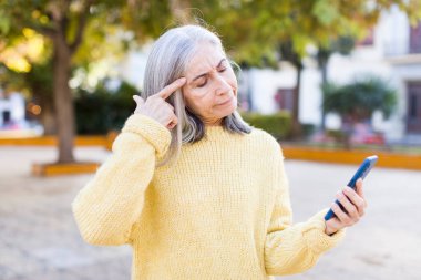 Güzel, son sınıf öğrencisi bir kadın şaşırmış görünüyor, akıllı telefonla yeni bir düşünce, fikir ya da konsept fark ediyor.