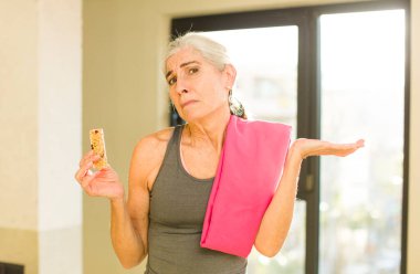 Kıdemli güzel kadın omuz silkiyor, kafası karışık ve kararsız hissediyor. fitness konsepti