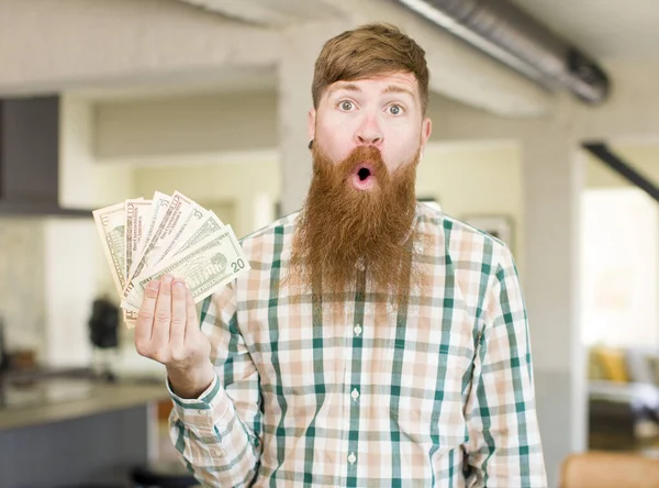 红头发的男人对美元钞票感到非常震惊和惊讶 — 图库照片