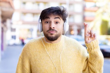 Genç yakışıklı adam şans diliyor ve şans diliyor. kulaklıkla müzik dinlemek