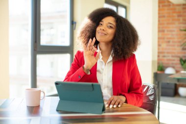 Güzel, afro siyah bir kadın kendini mutlu hissediyor. Onayını iyi bir jestle gösteriyor. iş kadını ve dizüstü bilgisayar konsepti