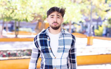 Genç yakışıklı adam üzgün ve mızmız, mutsuz bir bakışla, olumsuz ve hayal kırıklığına uğramış bir tavırla ağlıyor.