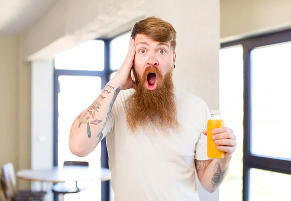 红头发的男人对橙汁瓶感到非常震惊和惊讶 — 图库照片
