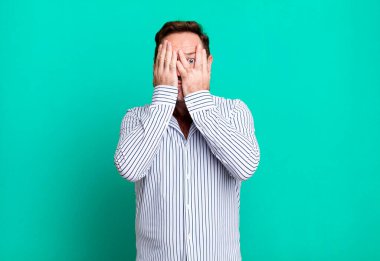 Yüzü ellerle kaplamak, parmaklarının arasından bakmak şaşırmış bir ifadeyle yan tarafa bakmak.