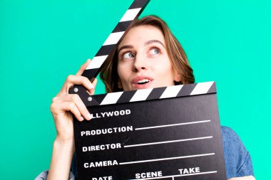 Genç ve güzel bir kadın, elinde alkışlı bir sinema tahtası tutuyor.
