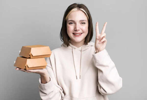 young pretty woman with burger boxes in the hands