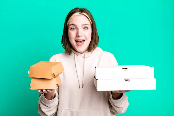 young pretty woman with pizza and burger boxes in the hands