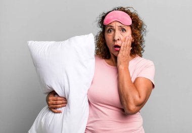 Güzel, orta yaşlı bir kadın pijama ve yastık giyerken şok olmuş ve korkmuş hissediyor.