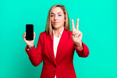 pretty blonde woman smiling and looking friendly, showing number two. businesswoman and a phone concept clipart