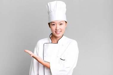 Güzel Asyalı kadın neşeyle gülümsüyor, mutlu hissediyor ve bir konsept gösteriyor. restoran şefi konsepti