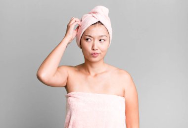 Güzel Asyalı kadın şaşkın ve kafası karışık, kaşınan bir kafa hissediyor. güzellik ve duş konsepti