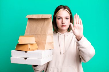 Genç ve güzel bir kadın ciddi görünüyor. Avuç içini gösteriyor. Durdurma hareketi yapıyor. Fast food konseptini kaldır.