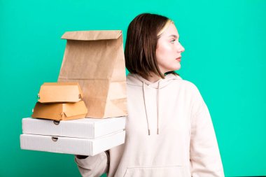 Profil görünümlü genç, güzel bir kadın hayal kuruyor ya da hayal kuruyor. Fast food konseptini kaldır.