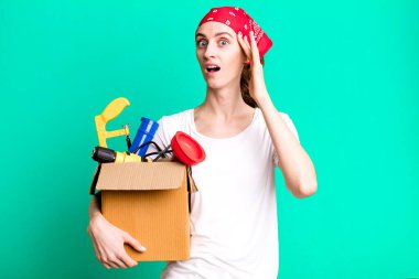 young pretty woman looking surprised, realizing a new thought, idea or concept. housekeeper and toolbox concept