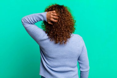 Orta yaşlı İspanyol kadın düşünüyor ya da şüphe ediyor, kafasını kaşıyor, kafası karışık ve kafası karışık, arkaya ya da arkaya bakıyor.