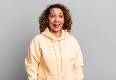 Orta yaşlı İspanyol bir kadın mutlu ve hoş bir şekilde şaşırmış görünüyor. Büyülenmiş ve şok olmuş bir ifadeyle heyecanlanıyor.