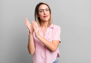 blonde adult woman feeling happy and successful, smiling and clapping hands, saying congratulations with an applause