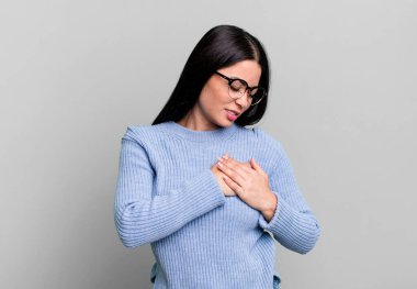 Güzel Latin bir kadın üzgün, yaralı ve kalbi kırık görünüyor, iki elini de kalbine yakın tutuyor, ağlıyor ve bunalımda.