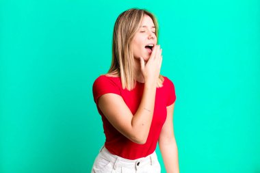 Sarışın, güzel bir kadın sabahın erken saatlerinde uykulu, yorgun ve sıkkın bir şekilde esniyor.