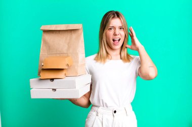 Genç ve güzel bir kadın ellerini havaya kaldırarak çığlık atıyor. Yemek teslimatı ve paket servis.