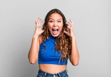 Genç ve güzel bir kadın ellerini havaya kaldırarak bağırıyor. Öfkeli, sinirli, stresli ve üzgün.