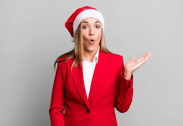 かなりブロンドの女が驚いてショックを受けて顎が物を持って落下した クリスマスとサンタの帽子のコンセプト — ストック写真