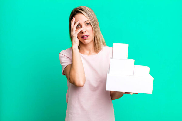 pretty blonde woman feeling bored, frustrated and sleepy after a tiresome with a set of blank packagings