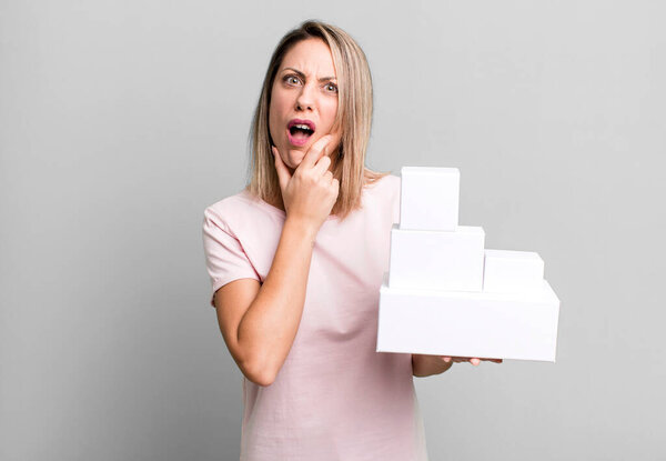 pretty blonde woman with mouth and eyes wide open and hand on chin with a set of blank packagings