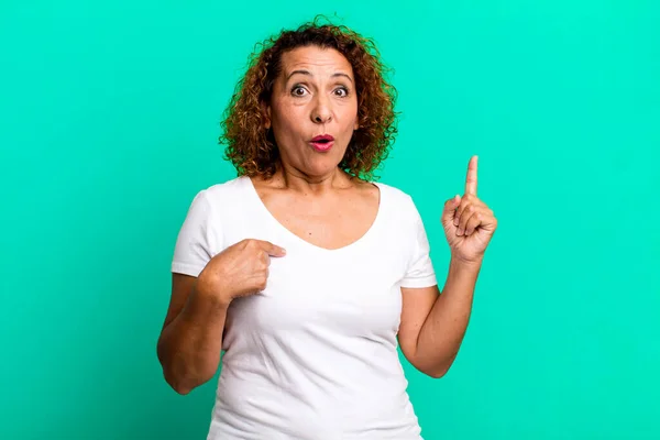 stock image middle age hispanic woman feeling proud and surprised, pointing to self confidently, feeling like successful number one