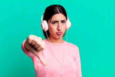 Çapraz hissetmek, baş parmakları aşağı göstermek. kulaklıkla müzik dinlemek