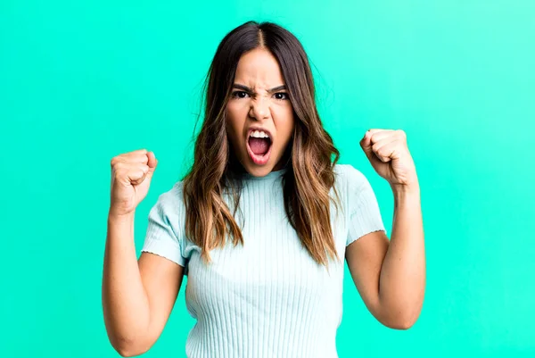 hispanic pretty woman shouting aggressively with an angry expression or with fists clenched celebrating success