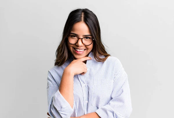 stock image hispanic pretty woman smiling, enjoying life, feeling happy, friendly, satisfied and carefree with hand on chin