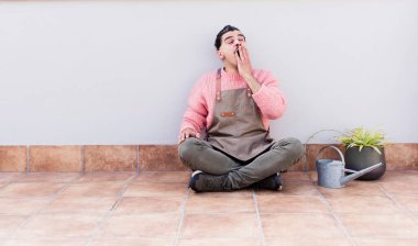 Genç yakışıklı adam gargara yapıyor ve dışarıda yerde oturuyor.