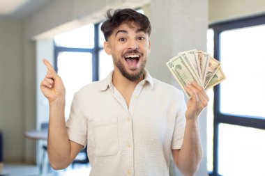 Genç yakışıklı bir adam bir fikri fark ettikten sonra mutlu ve heyecanlı bir dahi gibi hissediyor. Dolar banknotları konsepti