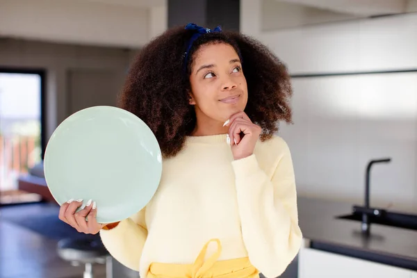 stock image pretty afro black woman smiling with a happy, confident expression with hand on chin. home chef concept