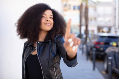 Afro-Amerikan güzel kadın gururla gülümsüyor ve bir numaralı pozu başarıyla veriyor, kendini lider gibi hissediyor.