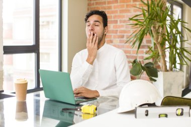 Genç İspanyol adam sabahın erken saatlerinde tembelce esniyor, uykulu, yorgun ve sıkılmış görünüyor. mimar konsepti