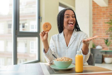 Siyah afro kadın mutlu bir şekilde gülümsüyor ve bir konsept sunuyor ya da gösteriyor. kahvaltı kavramı