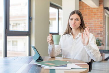 Genç ve güzel bir kadın ciddi görünüyor. Avuç içini gösteriyor. Durdurma hareketi yapıyor. Evden işe dolaşma kavramı