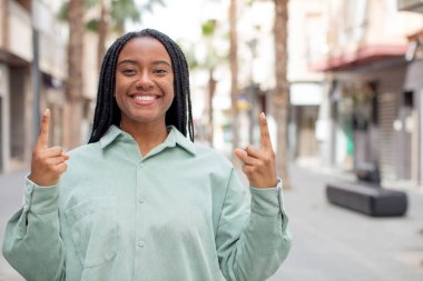 Afro güzel siyahi kadın hayranlık duyuyor ve ağzı açık. Şok olmuş ve şaşırmış bir şekilde yukarı bakıyor.
