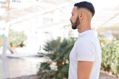 Profil görünümündeki genç yakışıklı adam ilerideki boşluğu kopyalamaya çalışıyor, düşünüyor, hayal ediyor ya da hayal kuruyor.