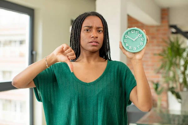 黒人アフロの女は十字架を感じ親指を下げて 目覚まし時計のコンセプト — ストック写真