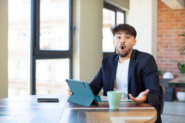 Genç ve yakışıklı bir adam şok olmuş ve şaşırmış hissediyor. dokunmatik ekran konsepti