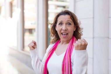 Orta yaşlı kadın şaşkın, heyecanlı ve mutlu hissediyor, gülüyor ve başarıyı kutluyor,!