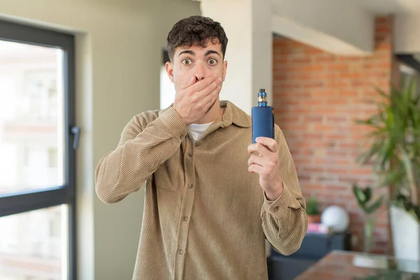 stock image young handsome man covering mouth with a hand and shocked or surprised expression. vaper smoking concept