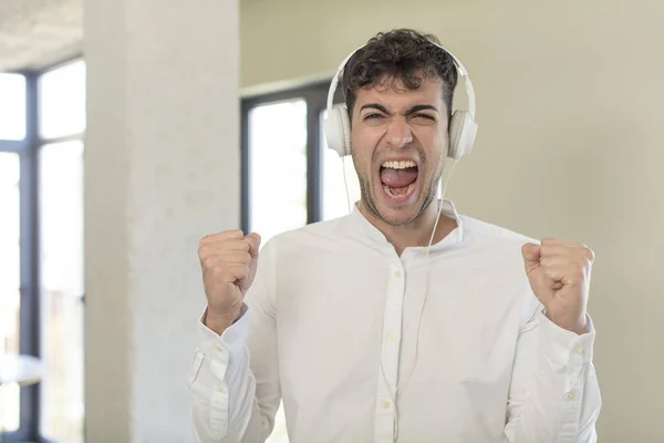 Genç Yakışıklı Adam Şok Olmuş Hissediyor Gülüyor Başarıyı Kutluyor Kulaklıkla — Stok fotoğraf
