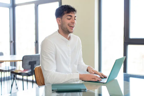 young handsome man smiling and looking with a happy confident expression. working at home concept