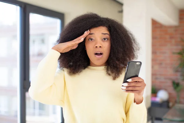かなりアフロ黒人女性は幸せそうで驚き驚きました スマートフォンのコンセプト — ストック写真