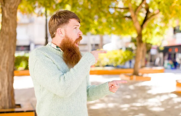 Red Hair Bearded Man Feeling Shocked Surprised Pointing Copy Space — Stock Photo, Image
